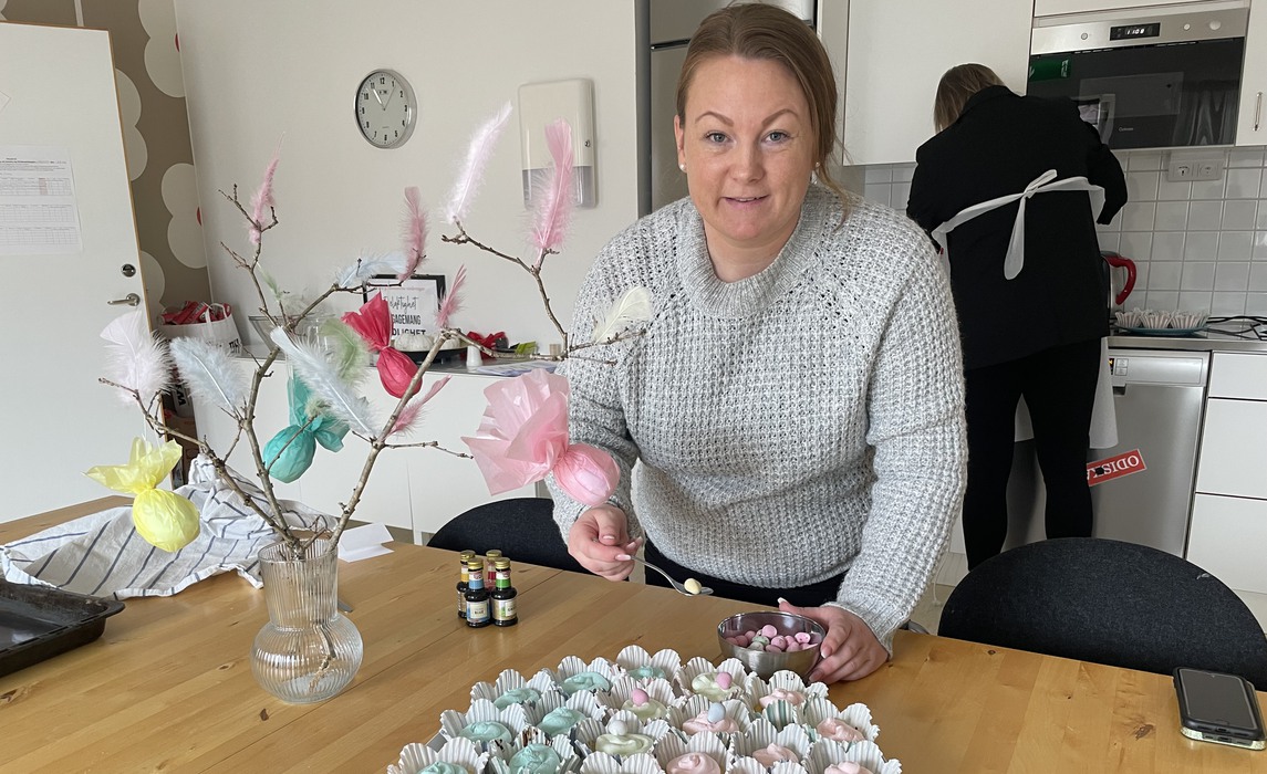 Christin Landqvist står vid ett bord och lägger godis på färgglada cupcakes.
