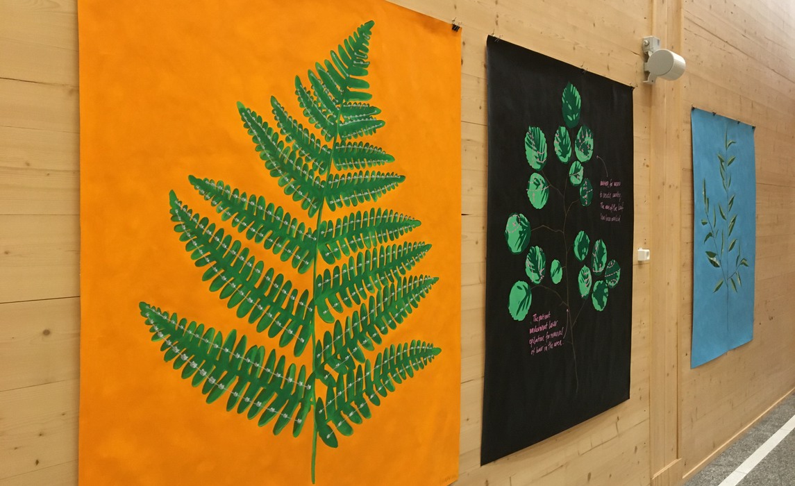 Konstverk hänger på väggen - motiv med gröna blad och växter