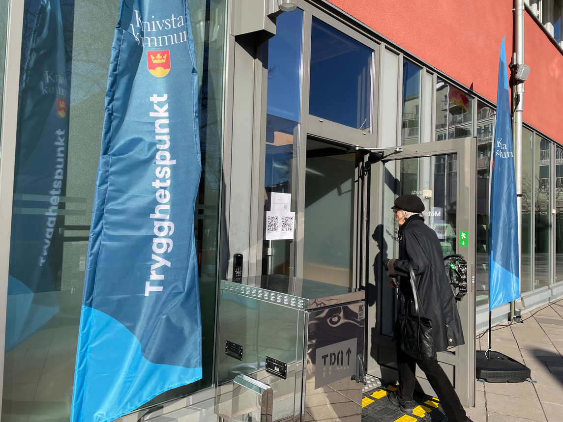 En kvinna i svarta kläder går in i en dörr med beachflaggor utanför.