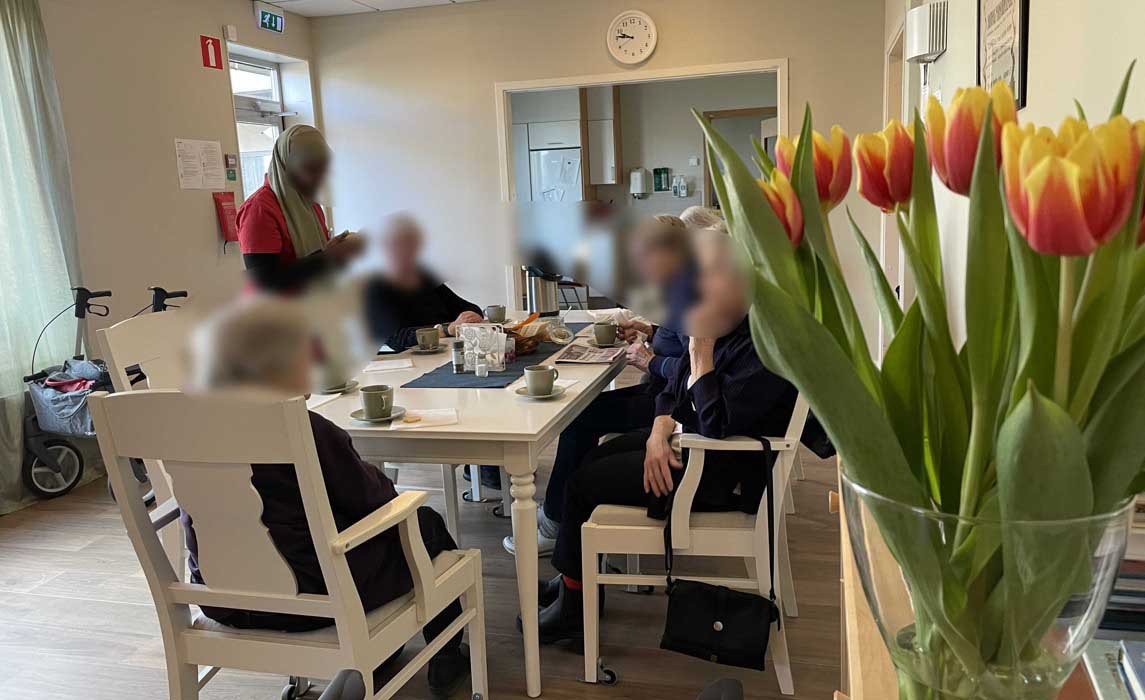 Personer sitter runt ett bord med en bukett tulpaner i förgrunden