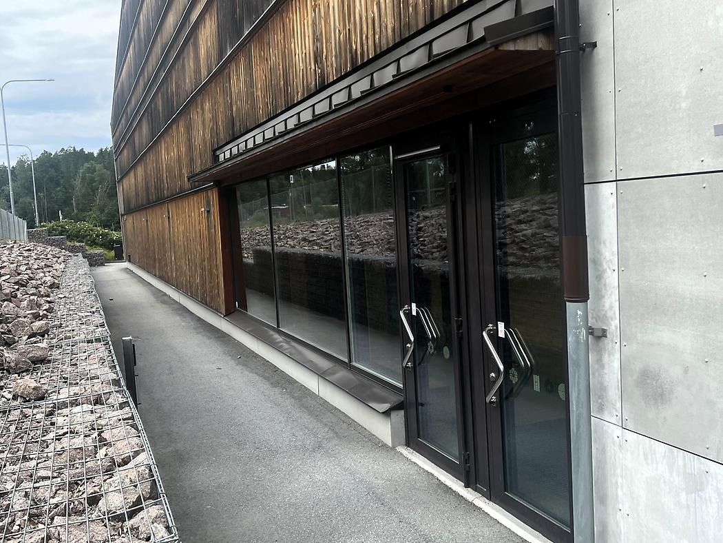 Byggnad med svarta dörrar och fasad i trä och betong.