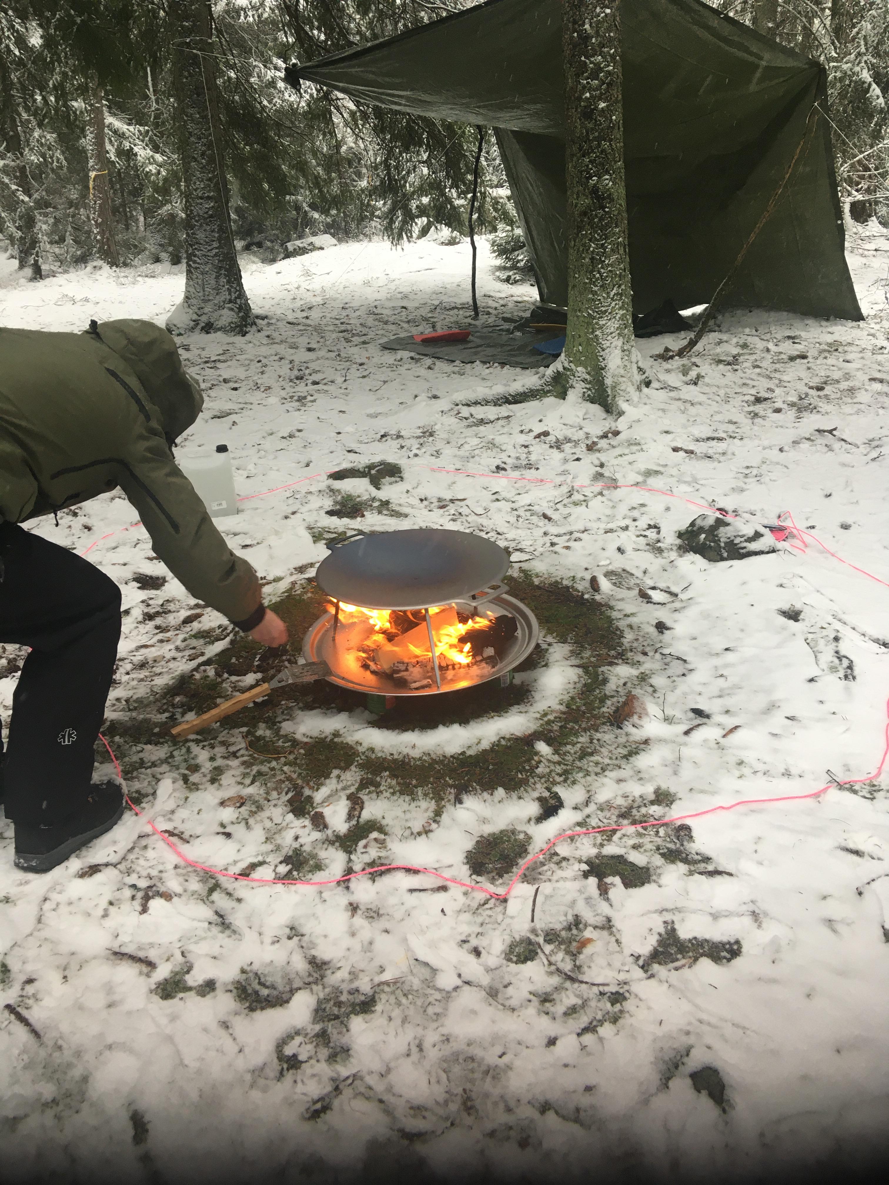 Muurika med brinnande eld och en lägerplats i skogen